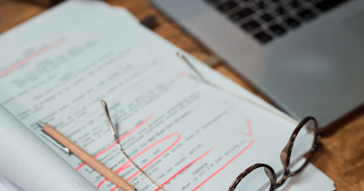 Documents and glasses beside a laptop on a working desk